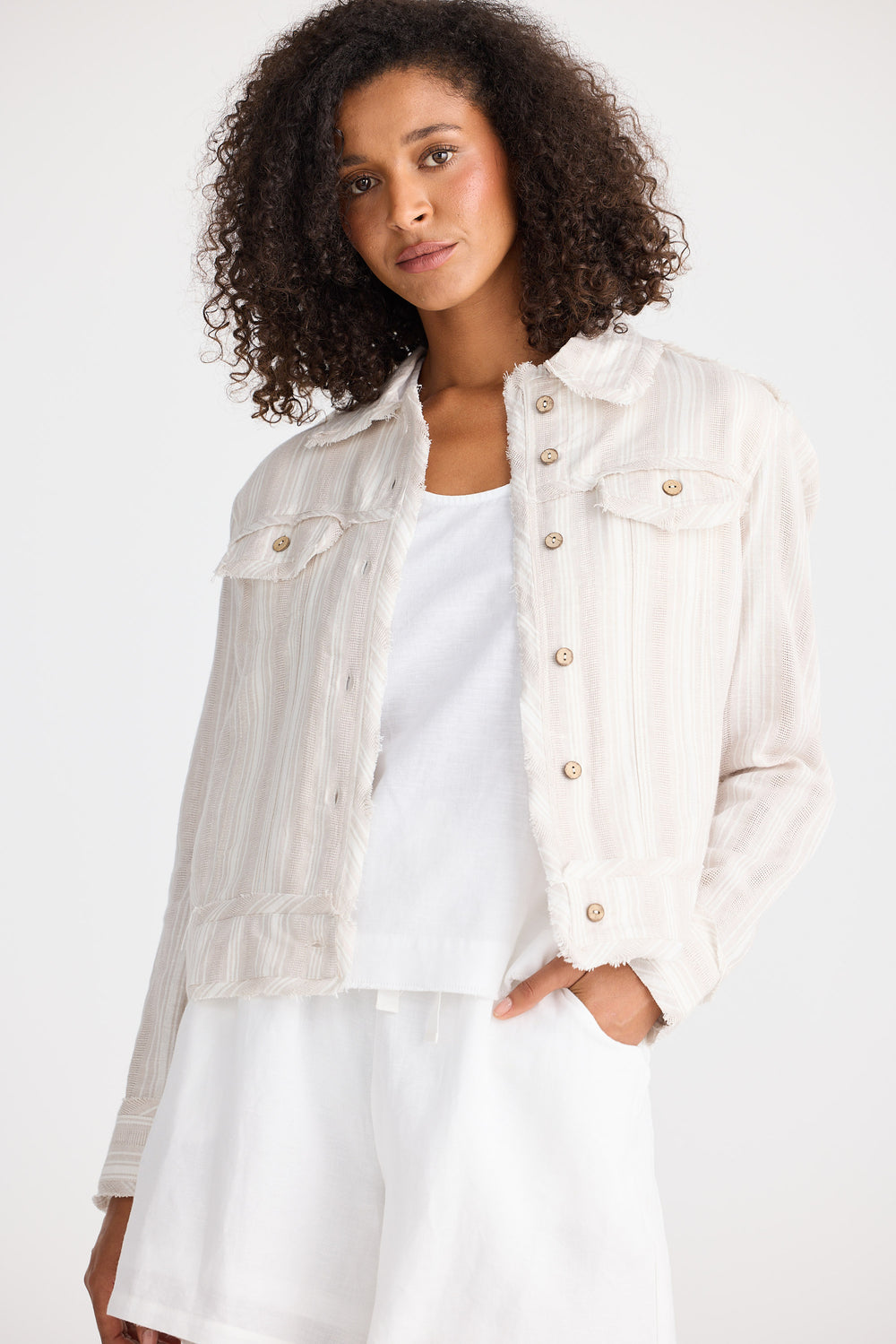 Woman wearing a light-coloured jacket over a white shirt on a plain background