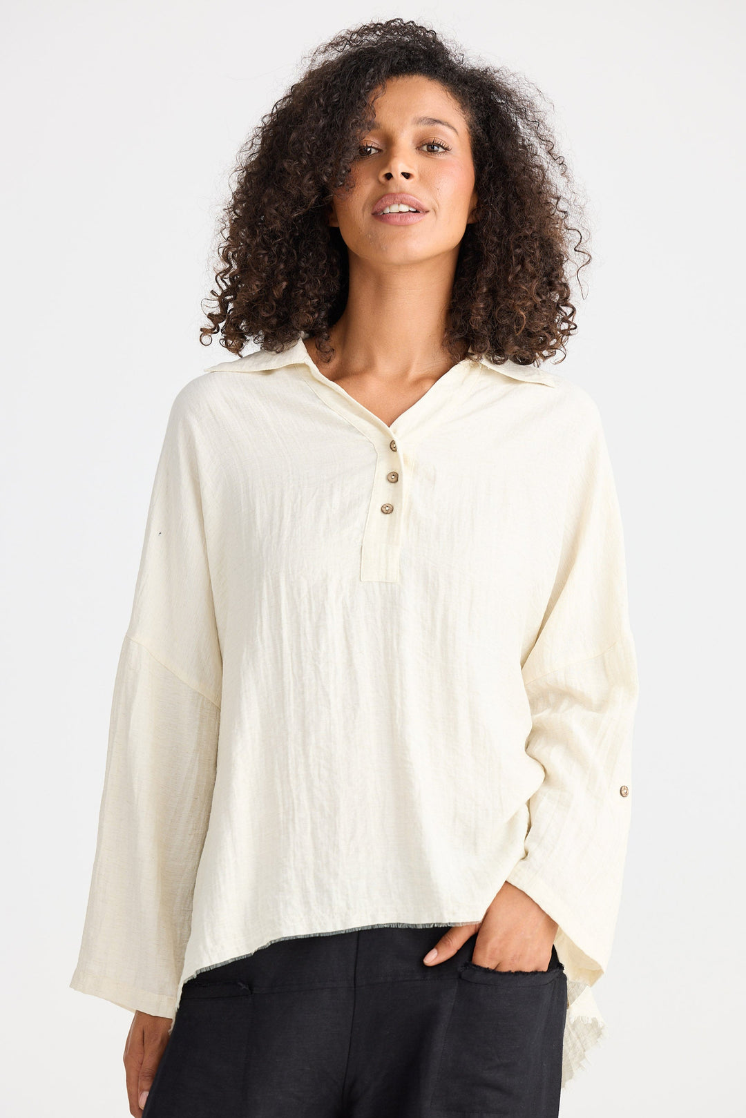 Woman wearing a cream-colored blouse with long sleeves on a white background