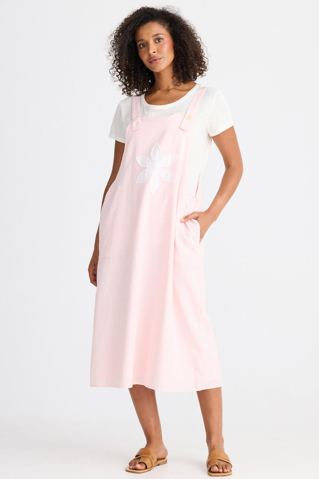Woman wearing a light pink dress over a white top on a white background