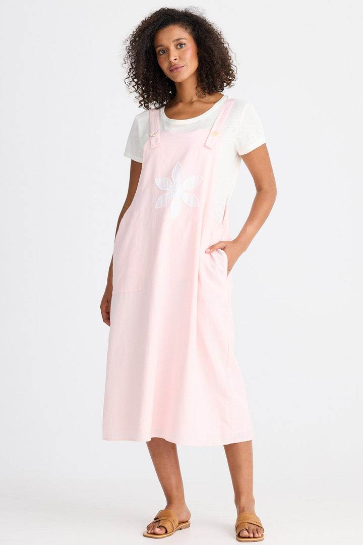 Woman wearing a light pink dress over a white top on a white background