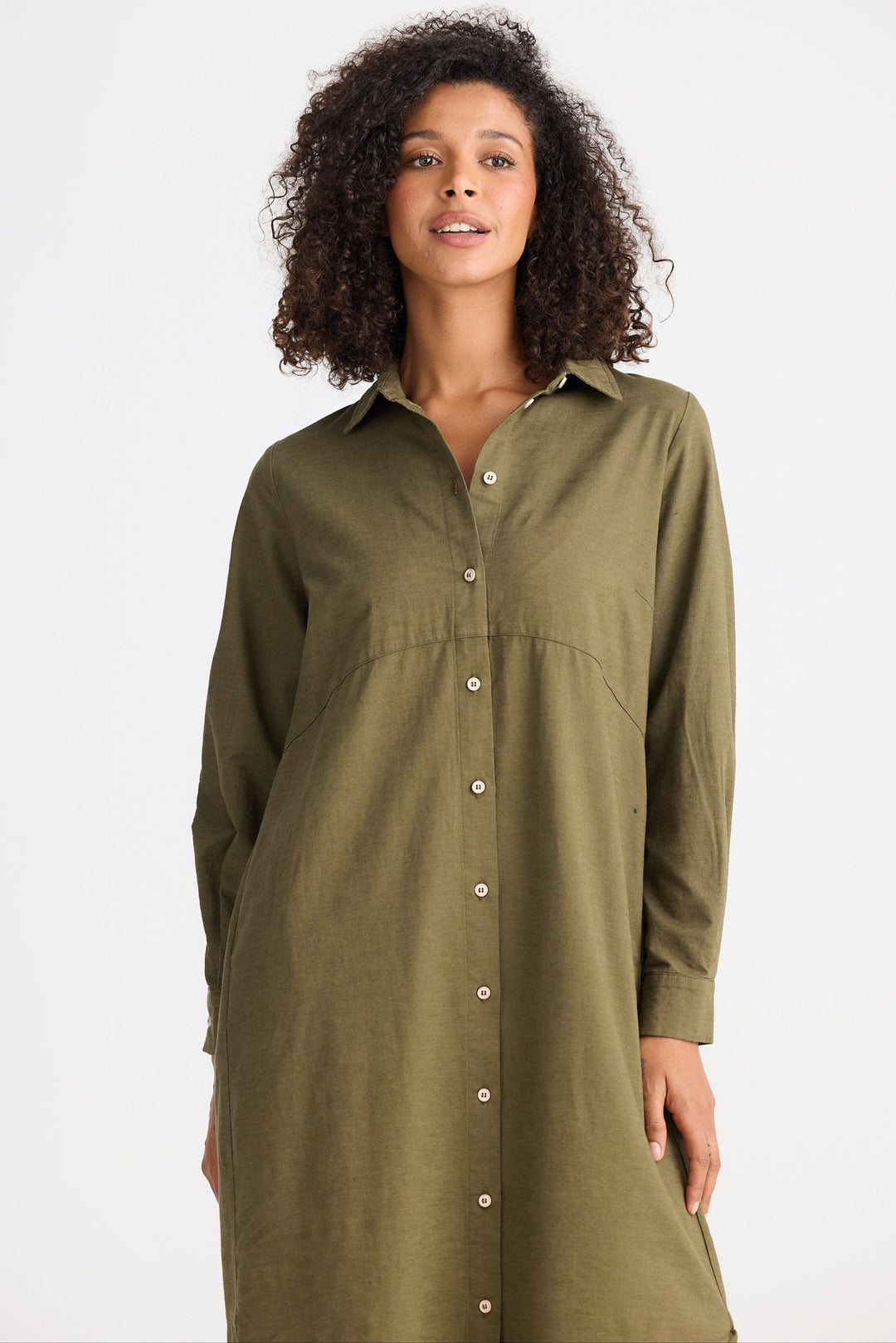 Woman wearing an olive green button-up dress against a white background