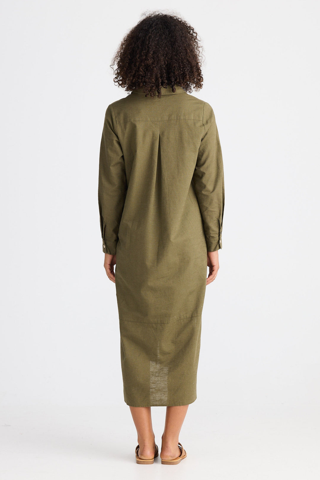 Person wearing a green dress standing against a white background