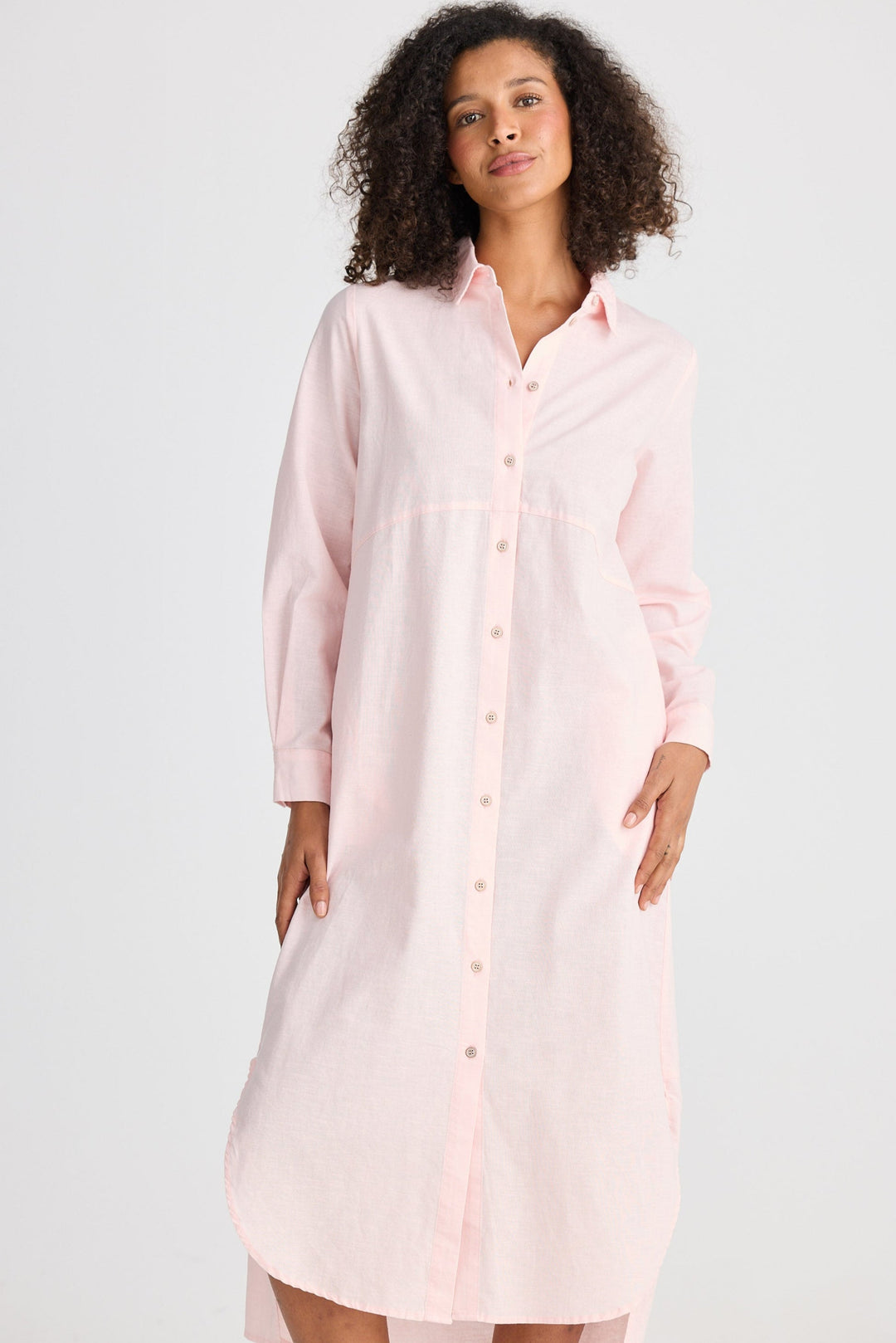 Woman wearing a light pink shirt dress on a white background