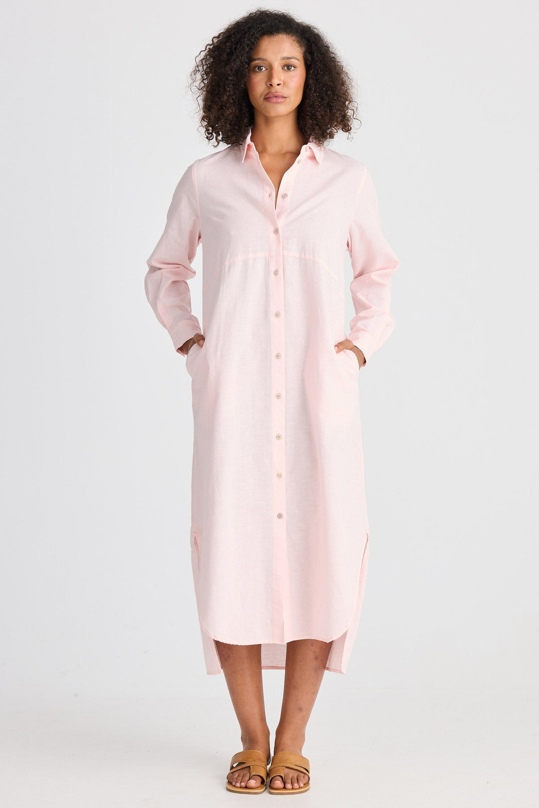Woman wearing a light pink shirt dress on a white background