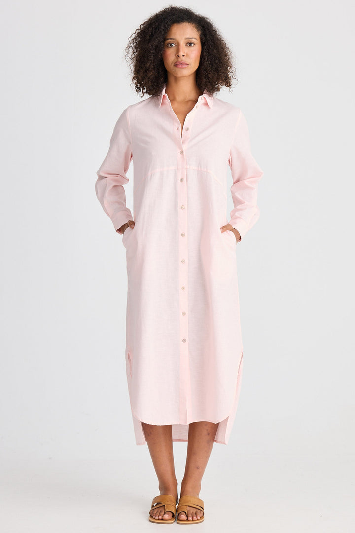 Woman wearing a light pink shirt dress on a white background