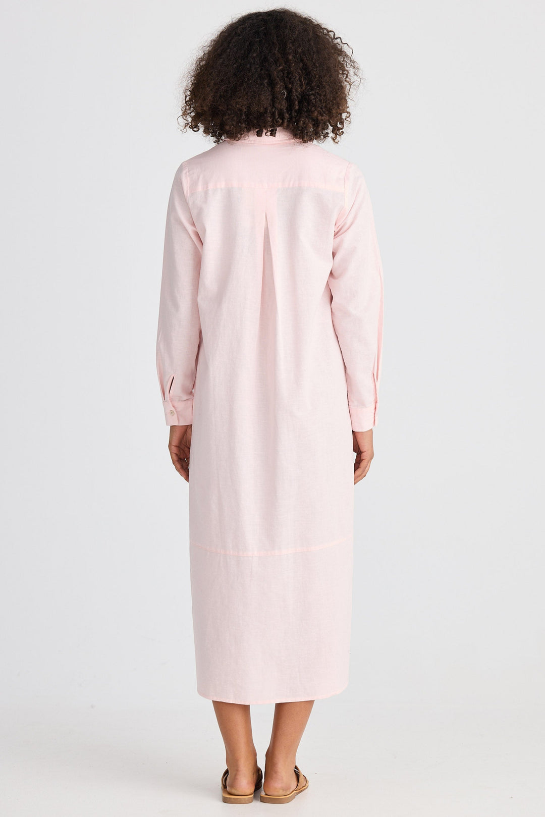Person wearing a light pink dress with long sleeves on a white background