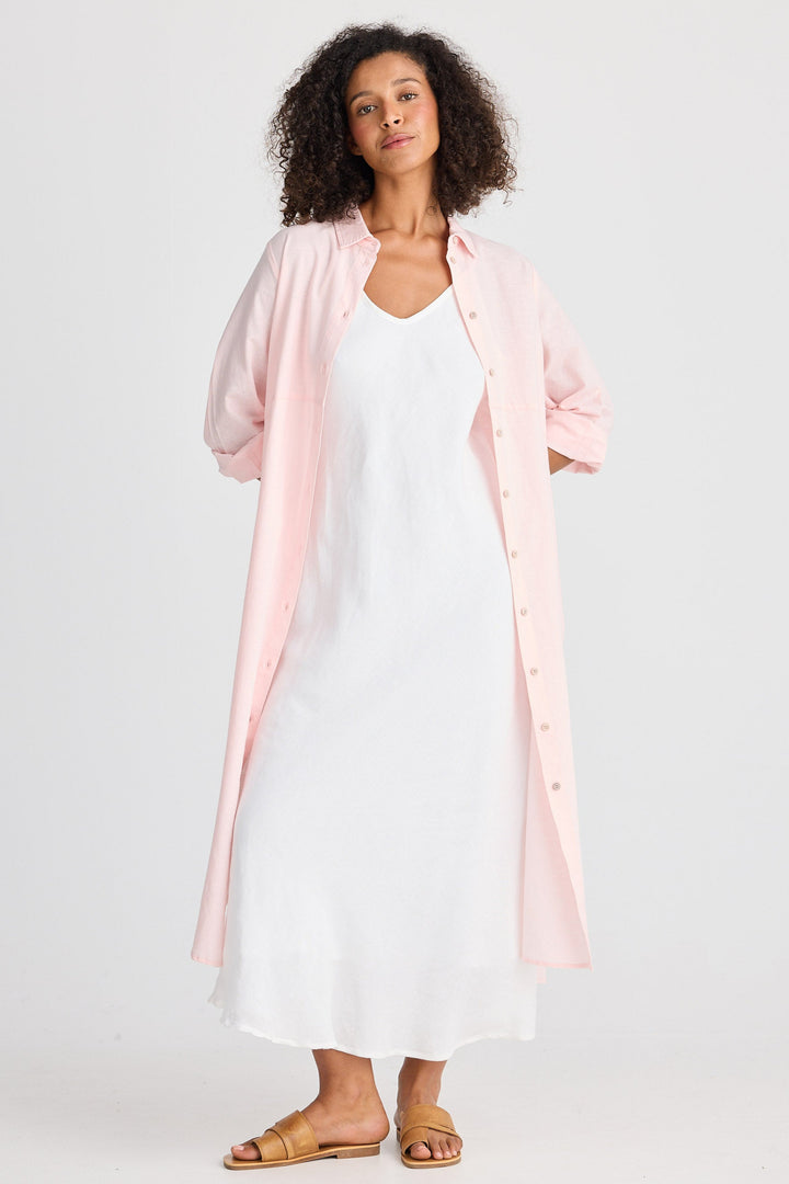 Woman wearing a white dress with a pink cardigan on a white background