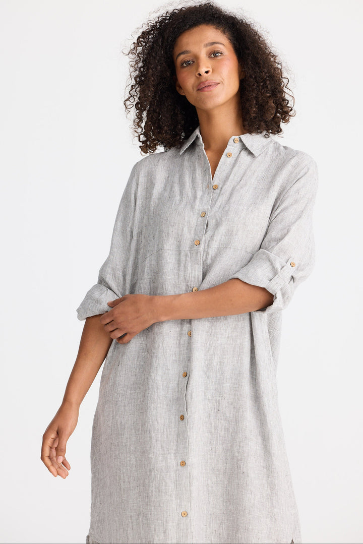 Woman wearing a light gray dress with rolled-up sleeves on a white background