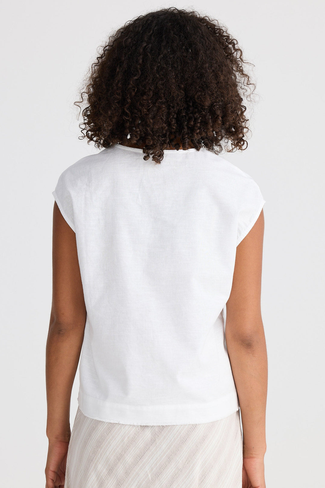 Person wearing a white sleeveless top on a plain background