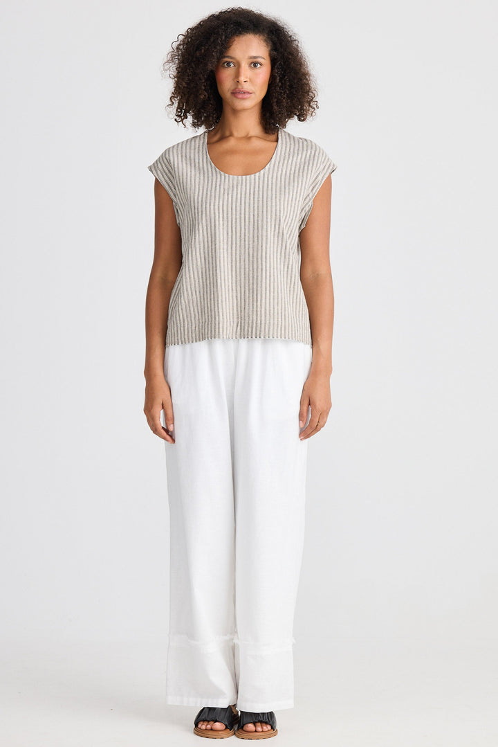 Woman wearing a striped top and white pants on a plain background
