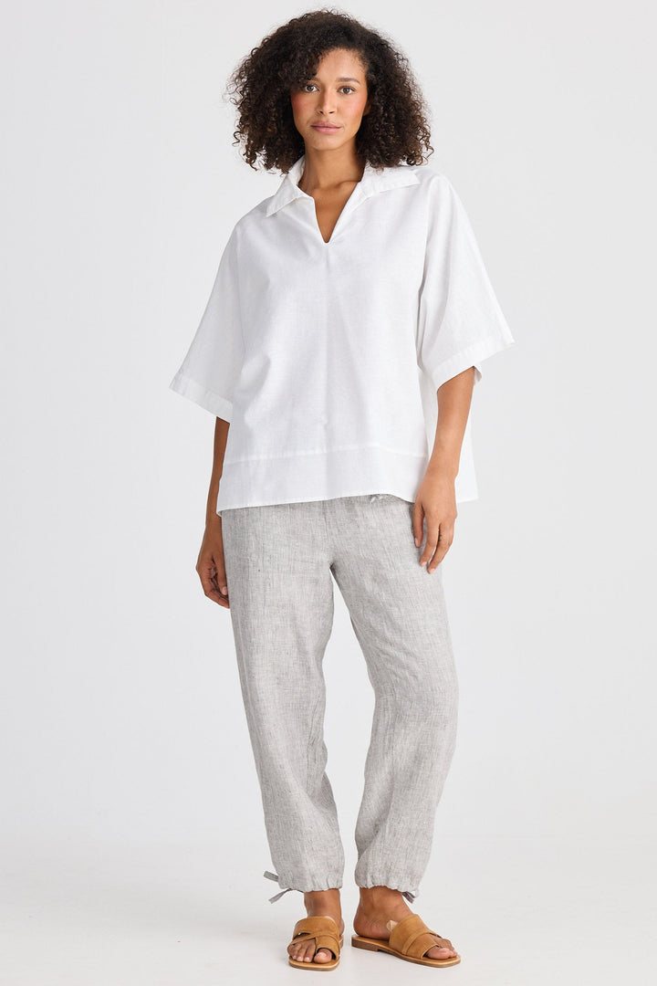 Woman wearing a white shirt and gray pants on a white background