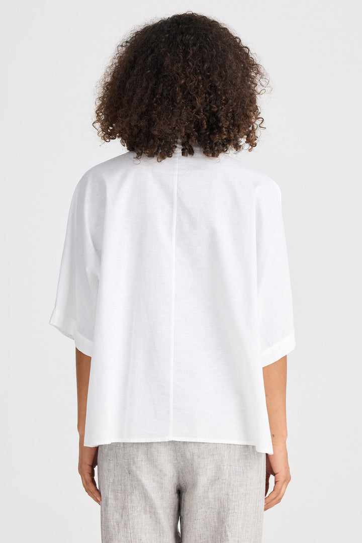 Person wearing a white blouse with a plain background