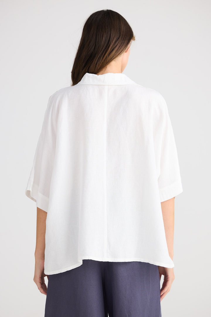 Person wearing a white shirt and dark pants on a plain background