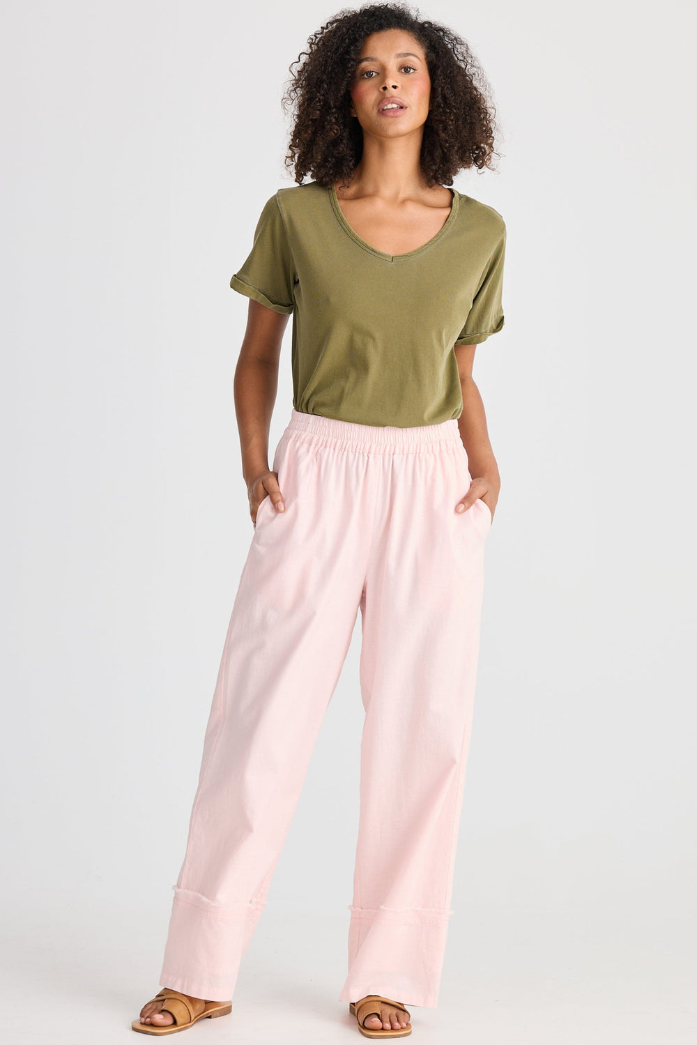 Woman wearing a green top and pink pants on a white background