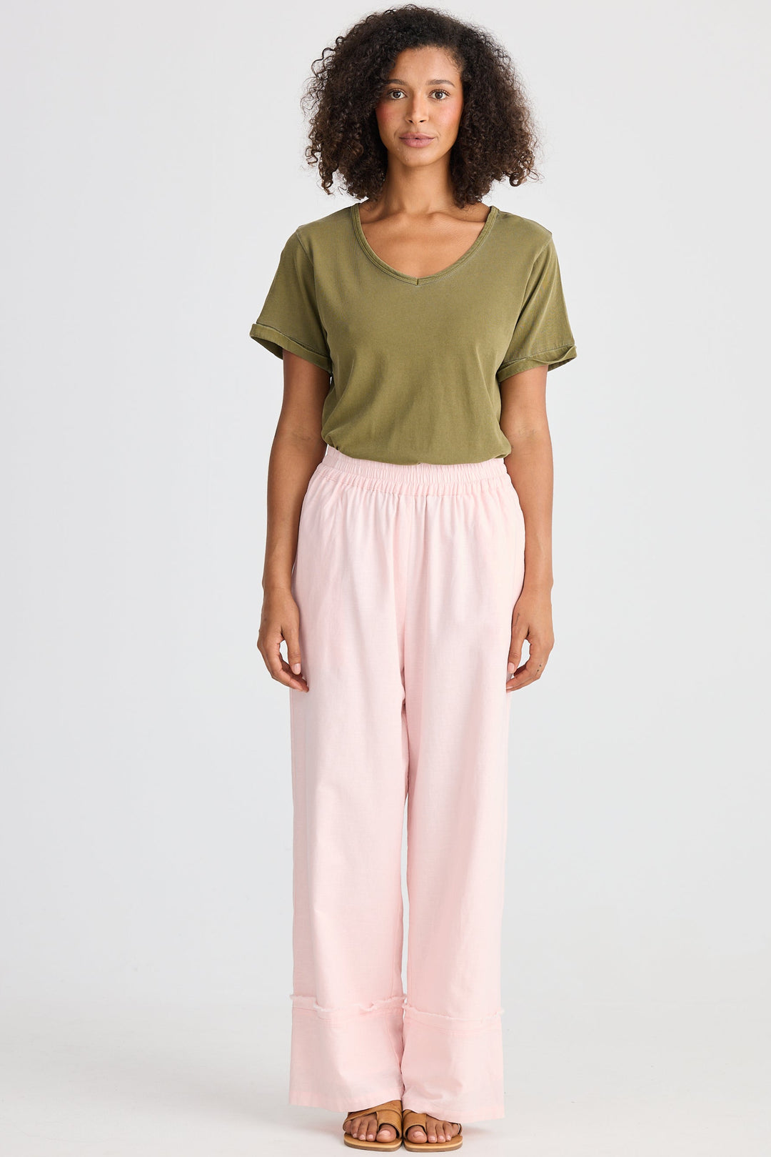 Woman wearing a green top and pink pants on a white background