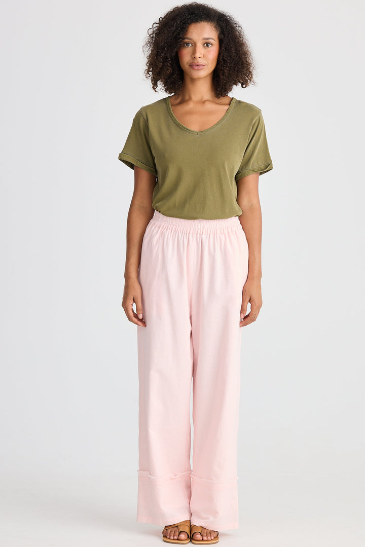 Woman wearing a green top and pink pants on a white background