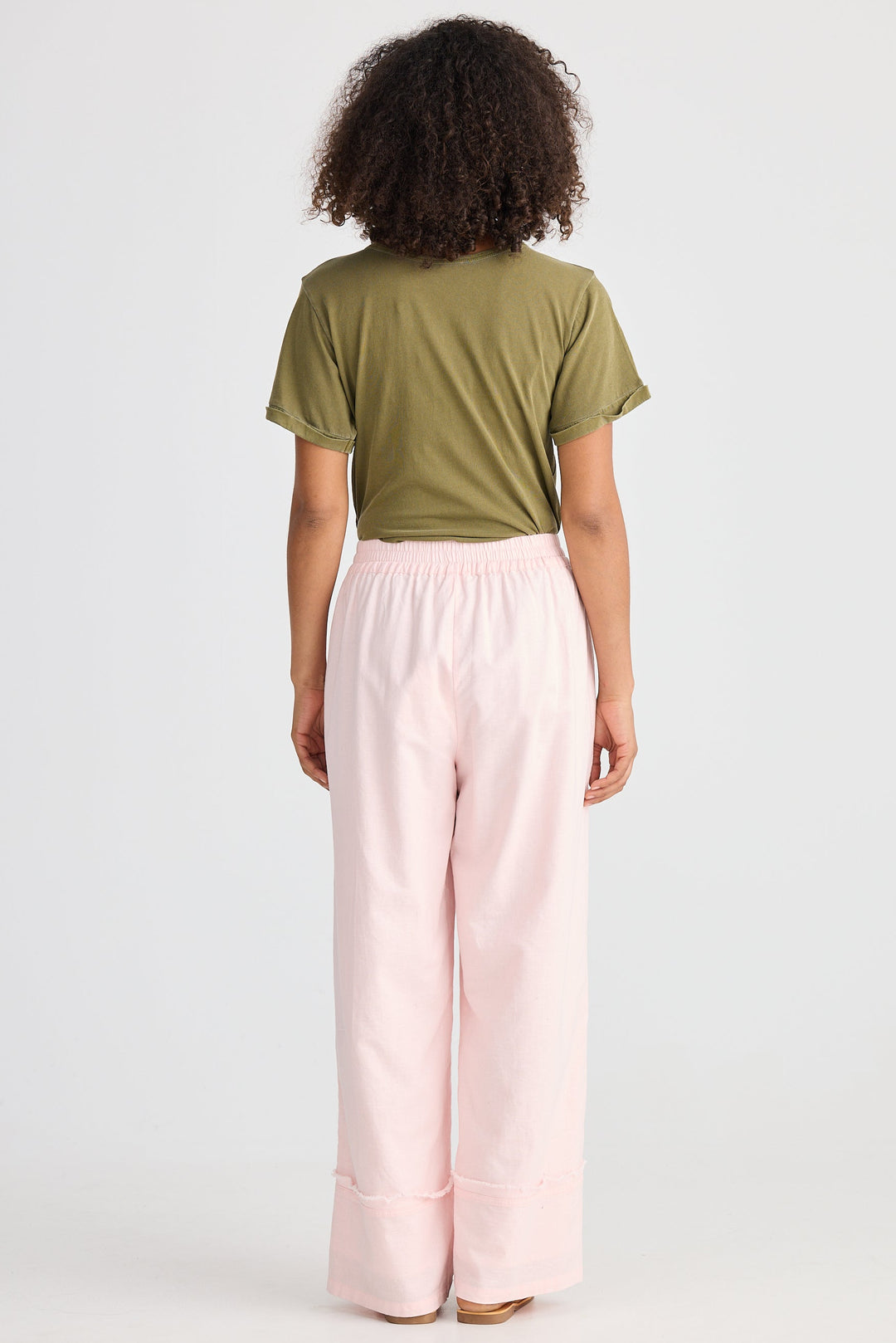 Person wearing a green top and pink pants on a white background