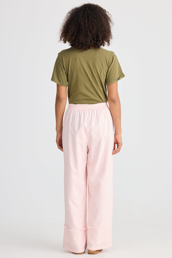 Person wearing a green top and pink pants on a white background