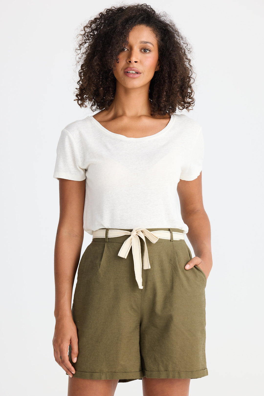 Woman wearing a white t-shirt and olive green shorts with a white background