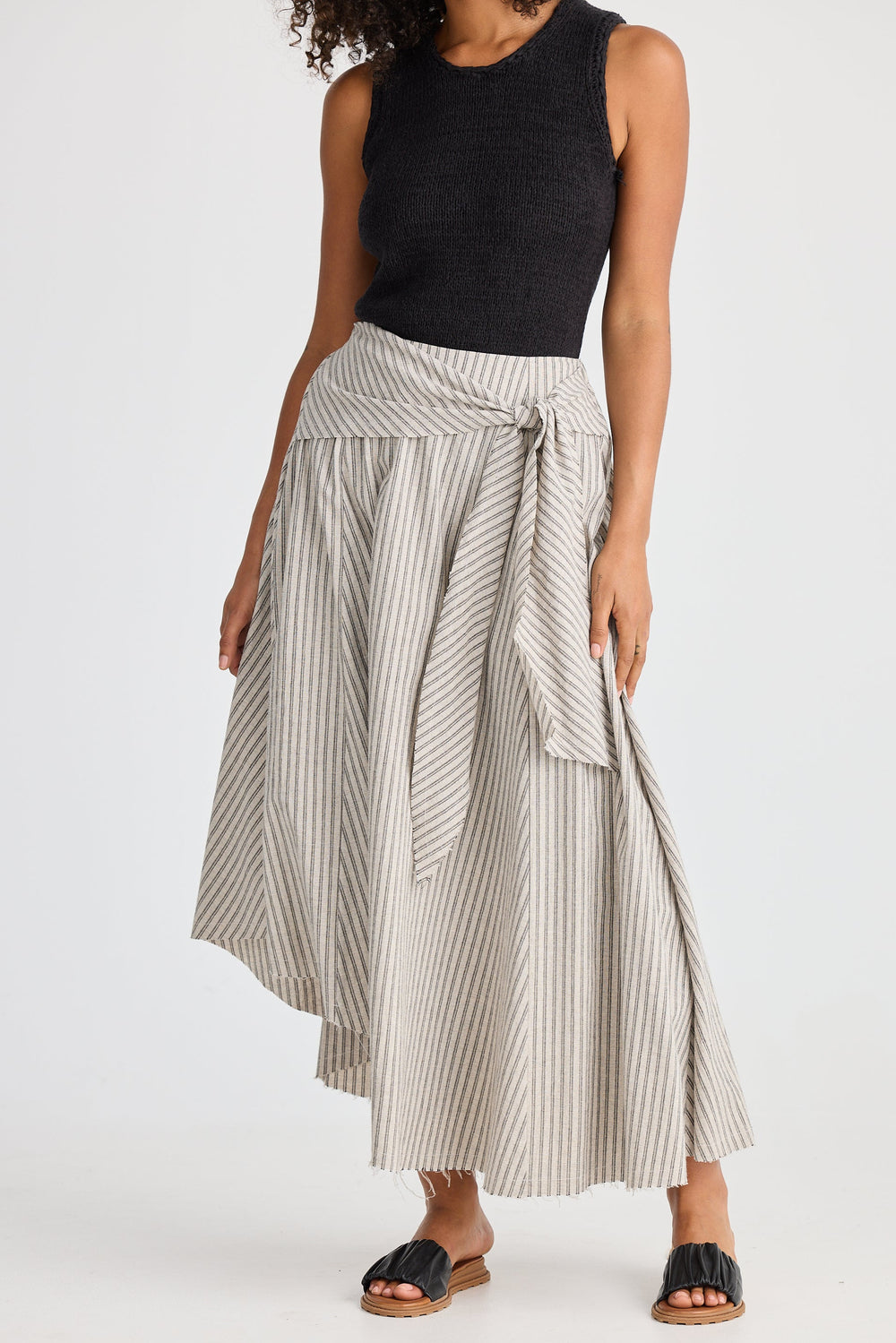 Woman wearing a black sleeveless top and striped skirt on a white background
