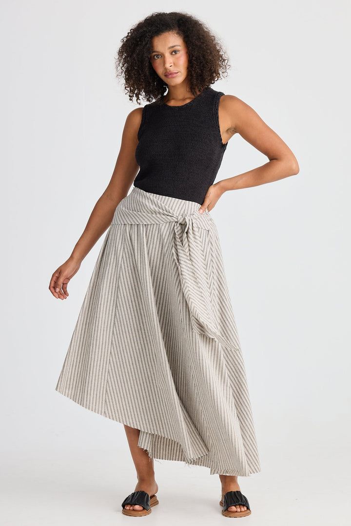 Woman wearing a black sleeveless top and striped skirt on a white background
