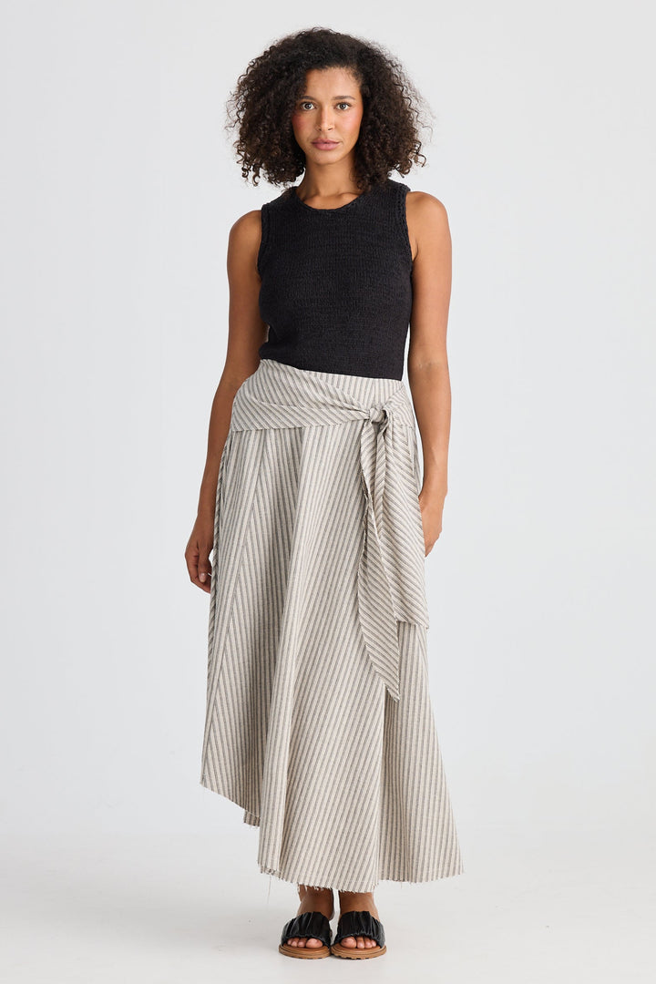 Woman wearing a black sleeveless top and striped skirt on a white background