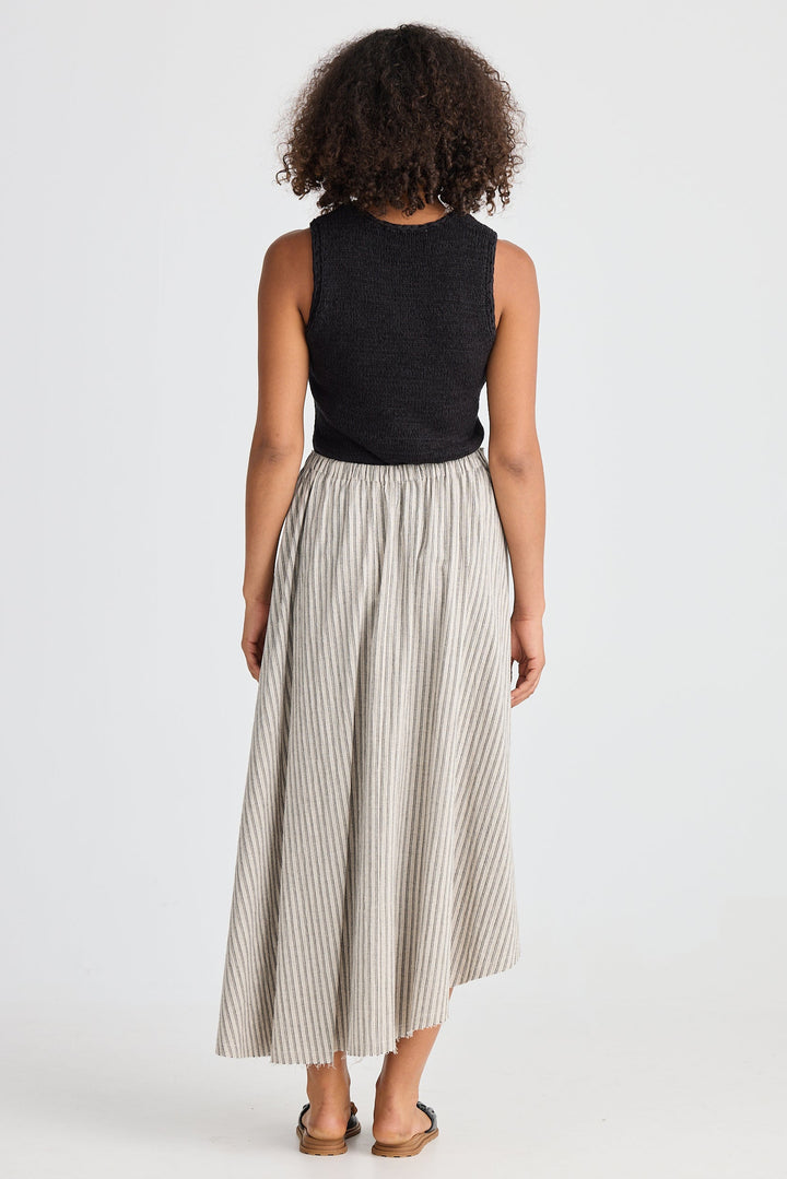 Woman wearing a black sleeveless top and striped skirt on a white background