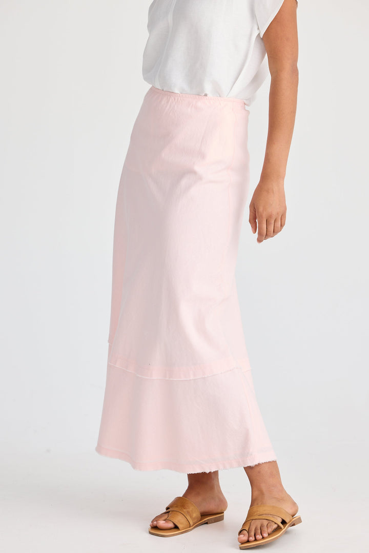Person wearing a light pink skirt and white top on a white background