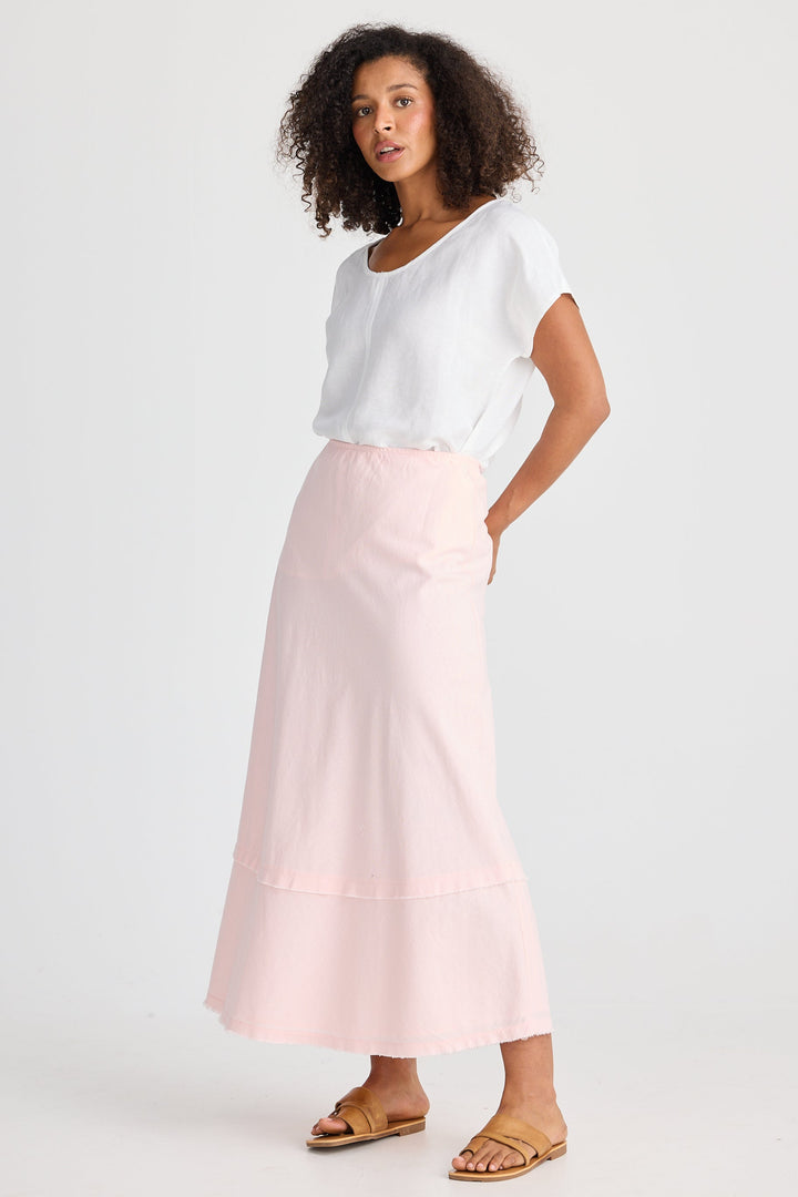 Woman wearing a white top and pink skirt on a white background