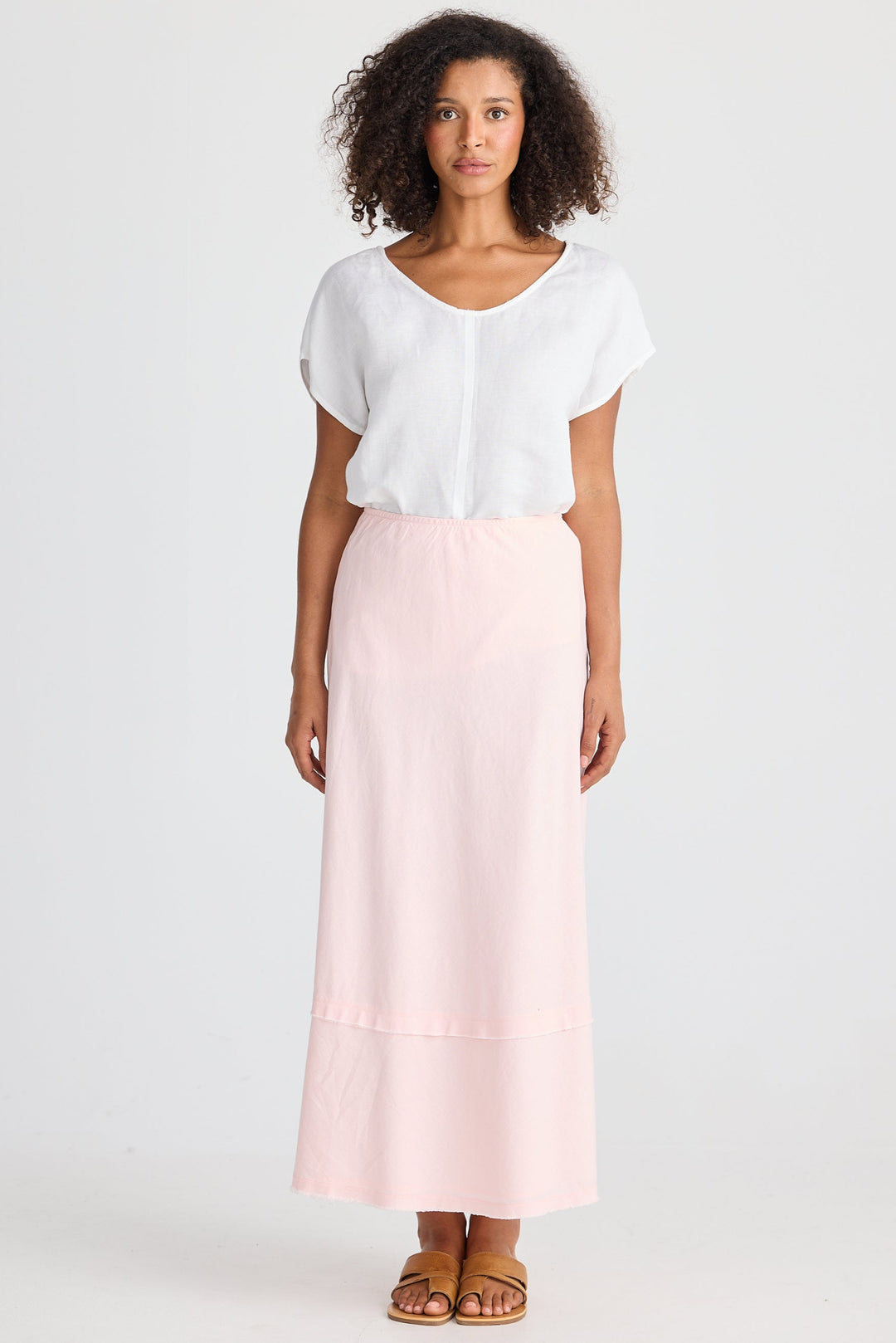 Woman wearing a white blouse and pink skirt on a white background