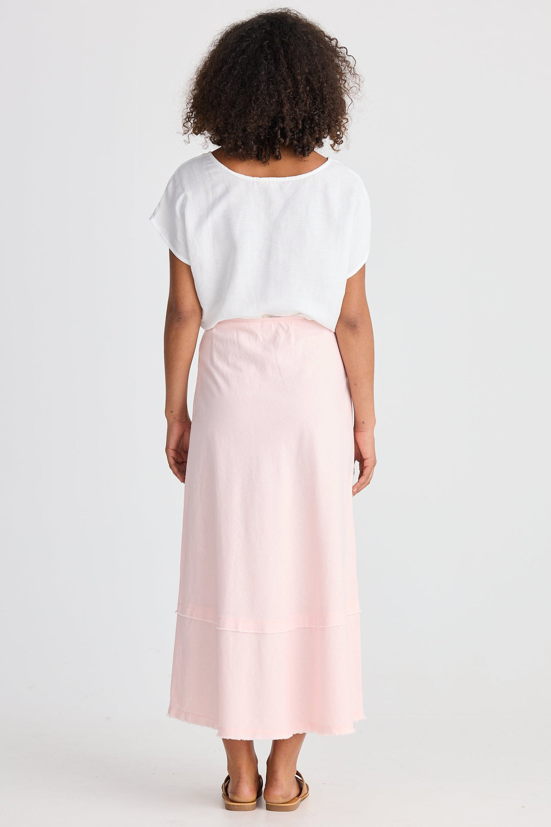 Person wearing a white top and light pink skirt on a white background