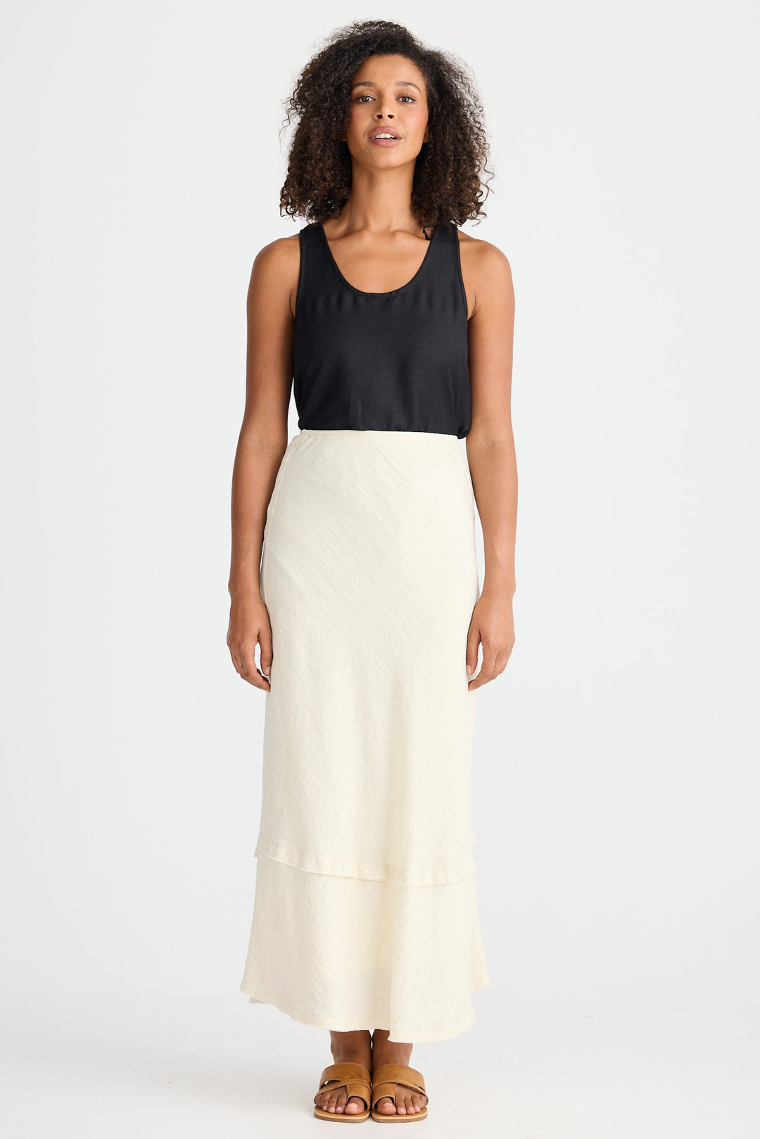 Woman wearing a black top and cream skirt on a white background