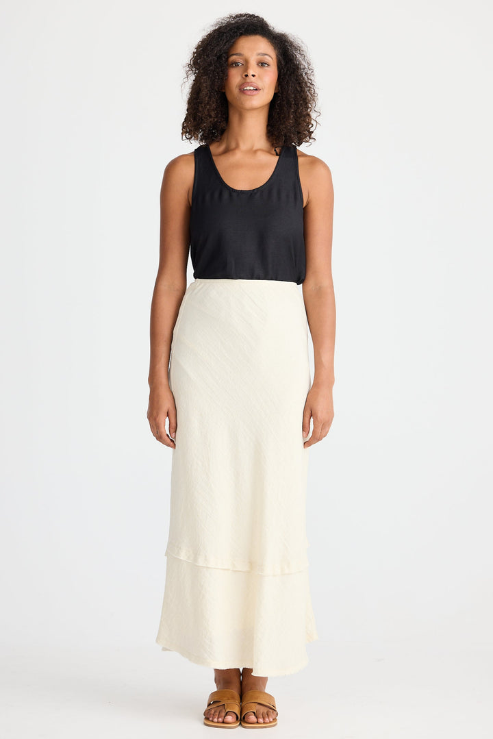 Woman wearing a black top and cream skirt on a white background
