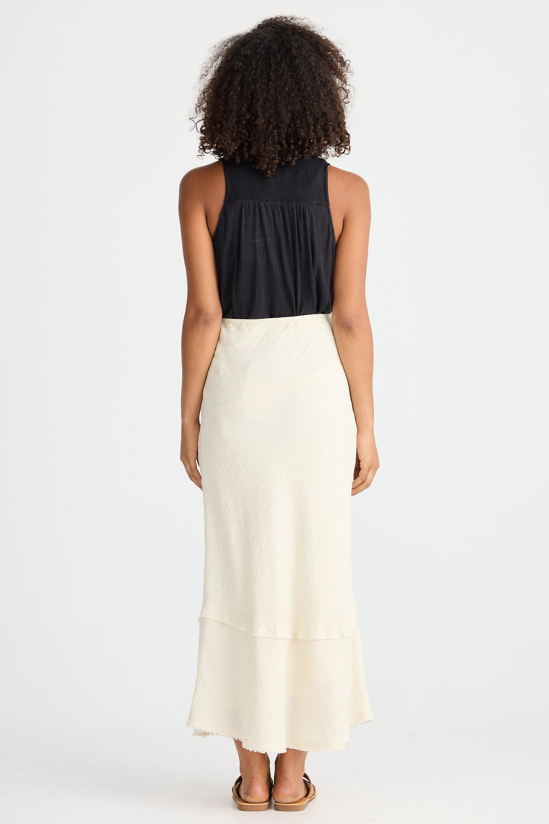 Person wearing a black top and cream skirt on a white background