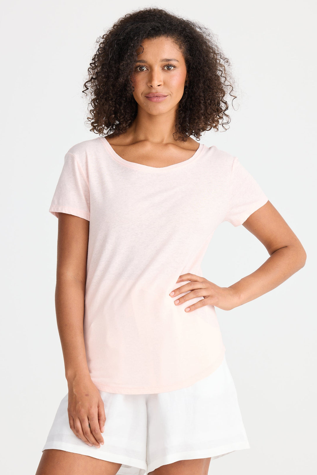 Woman wearing a light pink top and white shorts on a white background