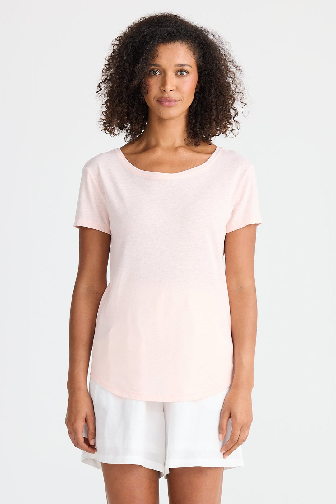 Woman wearing a light pink top and white shorts on a white background