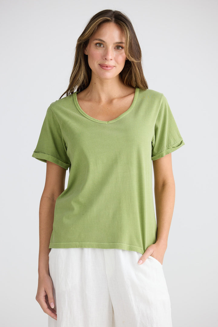 Woman wearing a green t-shirt and white pants on a plain background