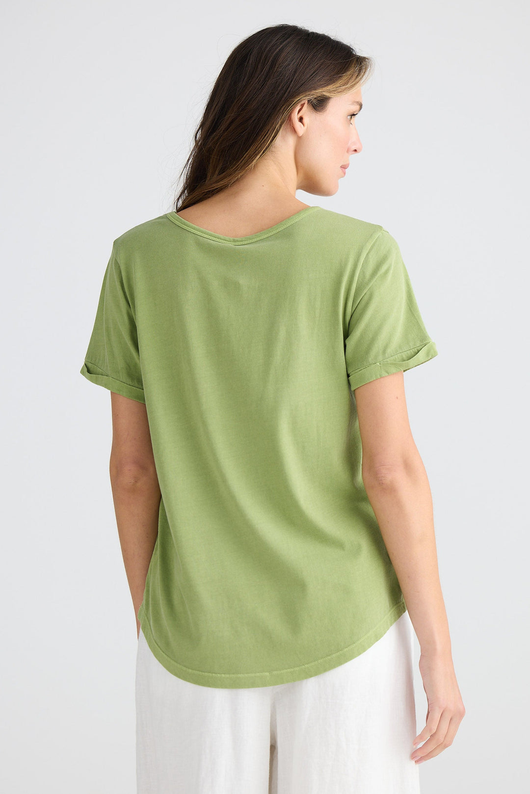 Woman wearing a green t-shirt and white pants on a white background