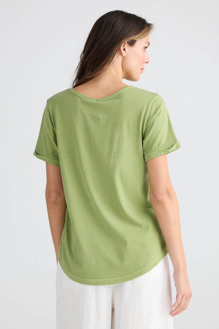 Woman wearing a green t-shirt and white pants on a white background