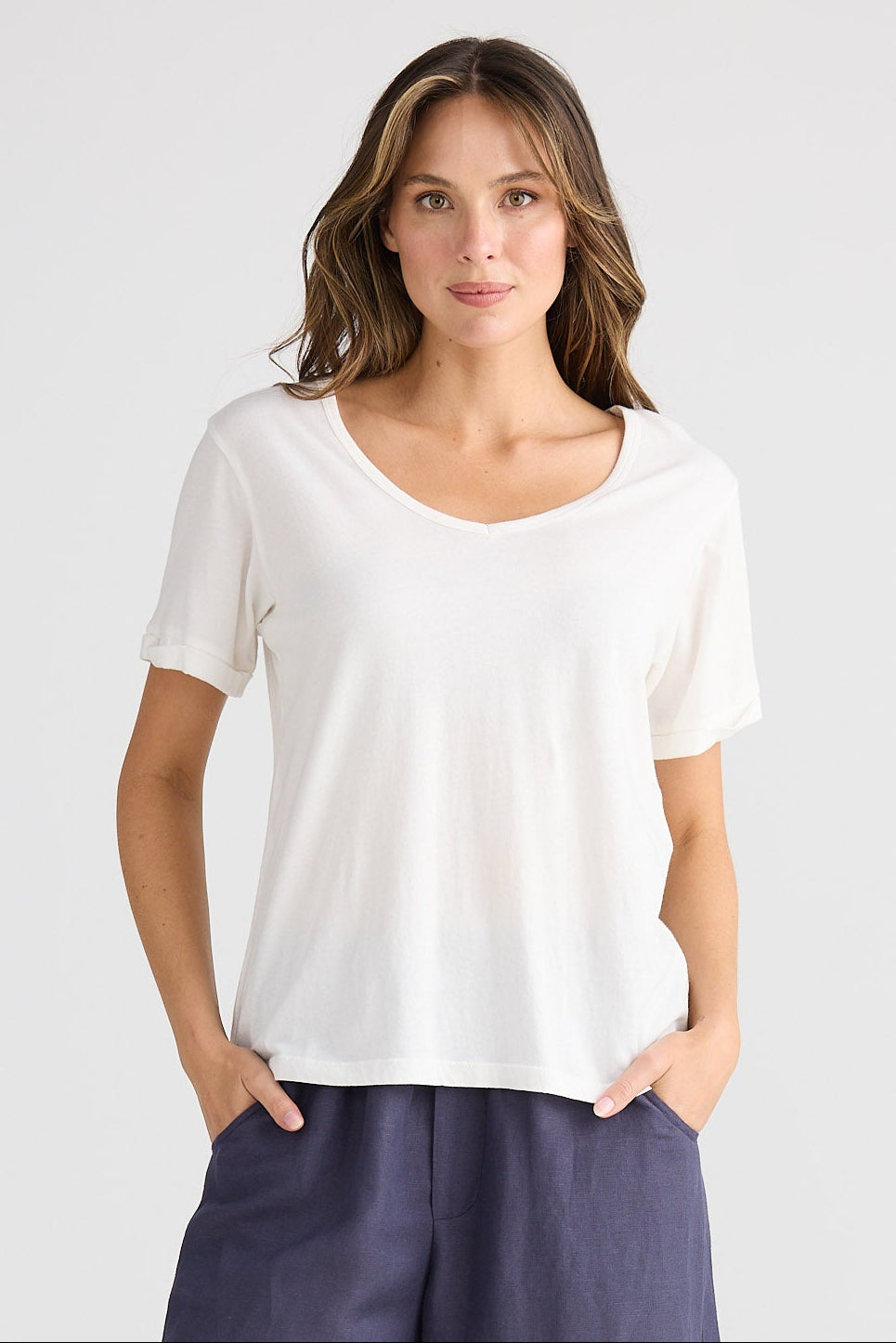 Woman wearing a white top and dark blue wide-leg pants on a light gray background