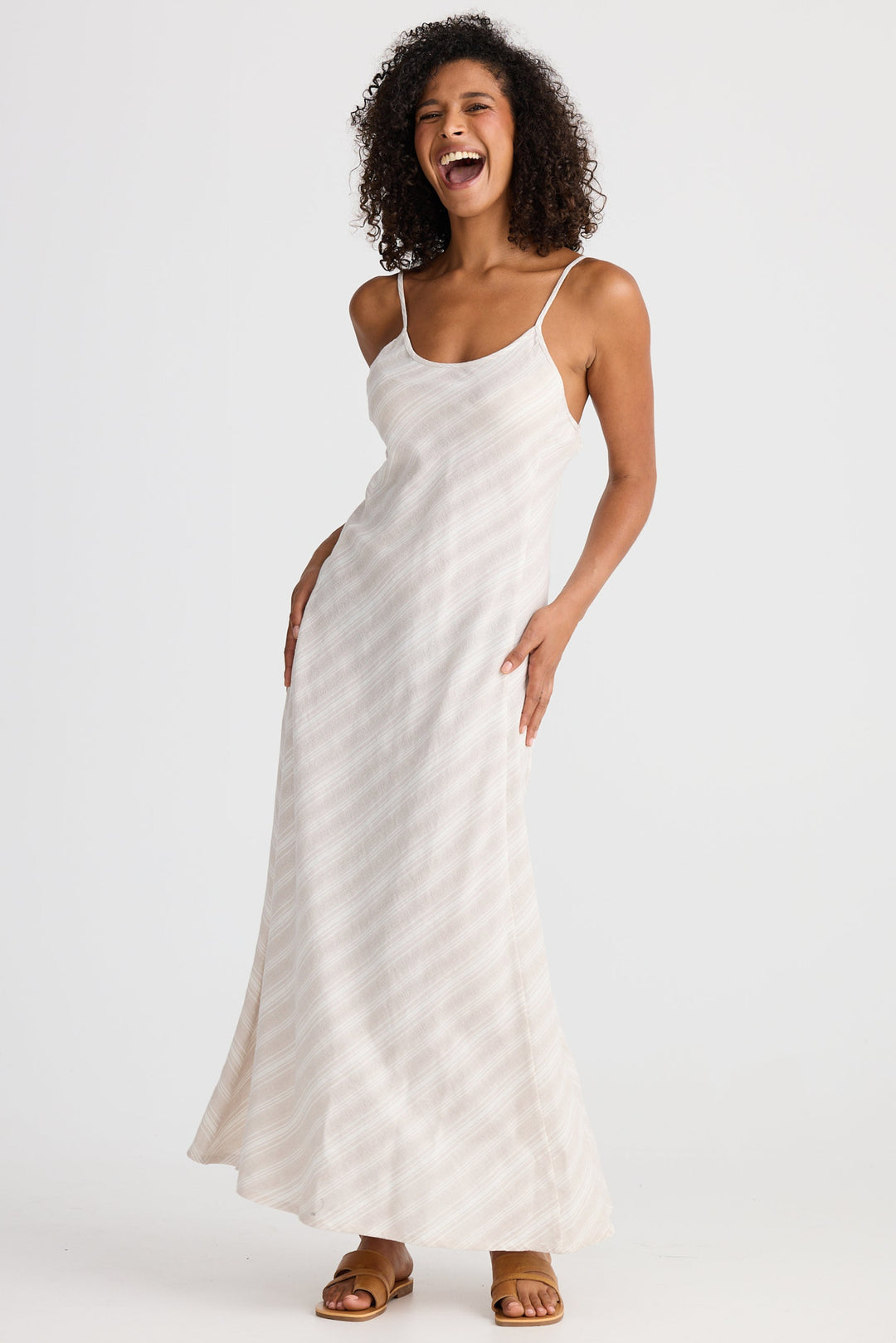 Woman wearing a light striped slip dress on a white background