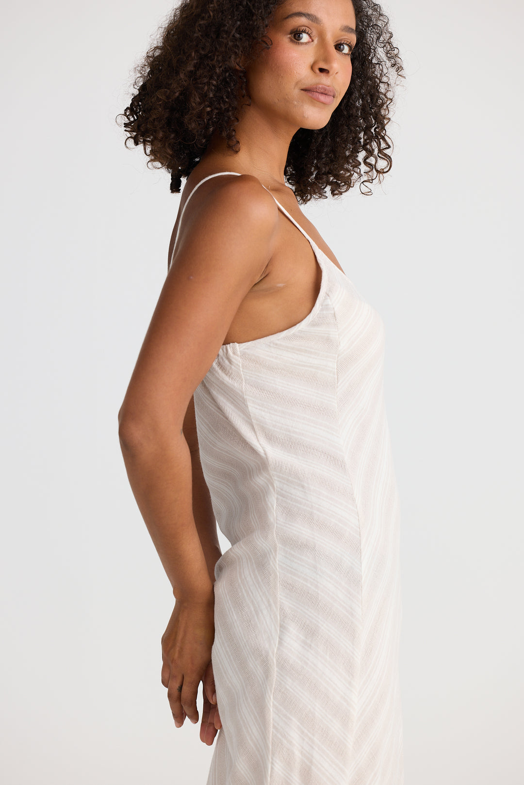 Woman wearing a light striped dress against a plain background