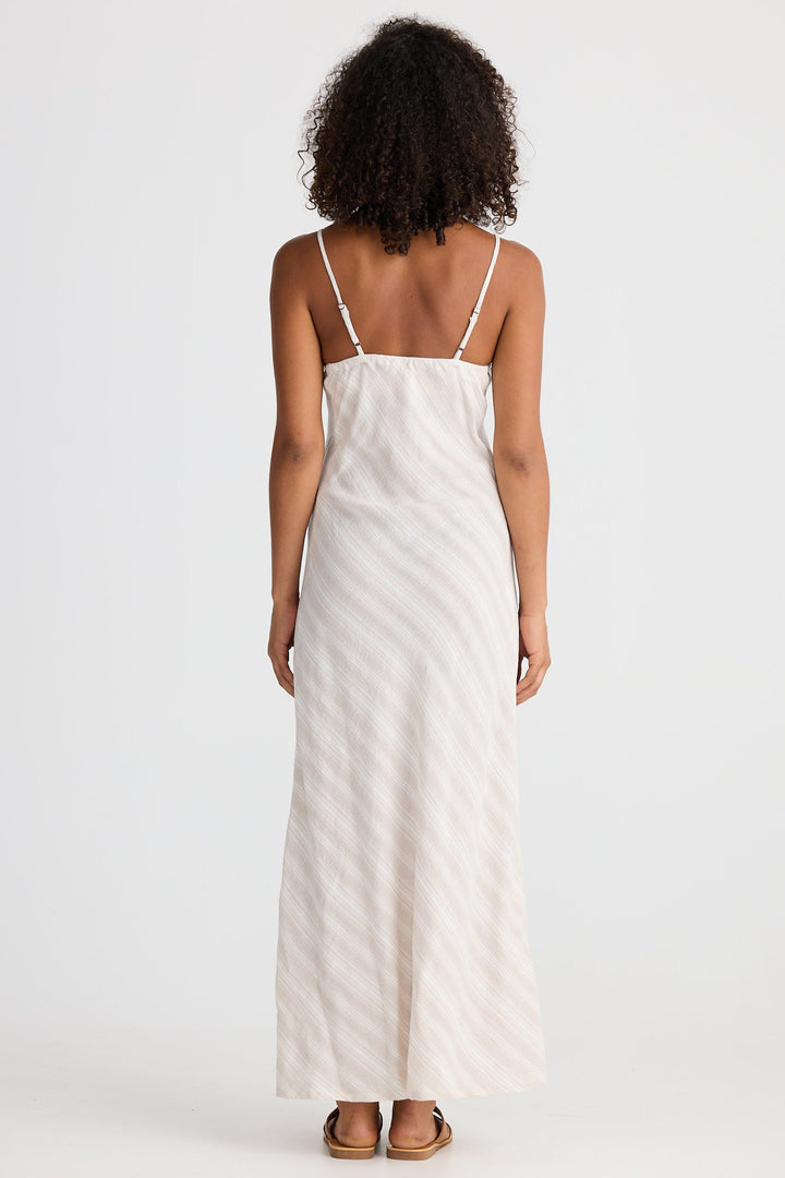Woman wearing a light striped dress with thin straps on a white background