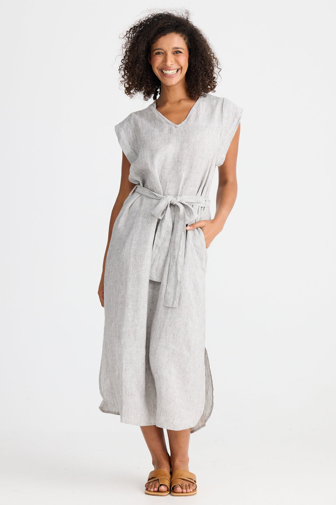 Woman wearing a light gray dress with a belt on a white background