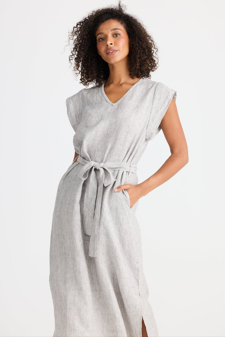 Woman wearing a light gray dress with a belt on a white background