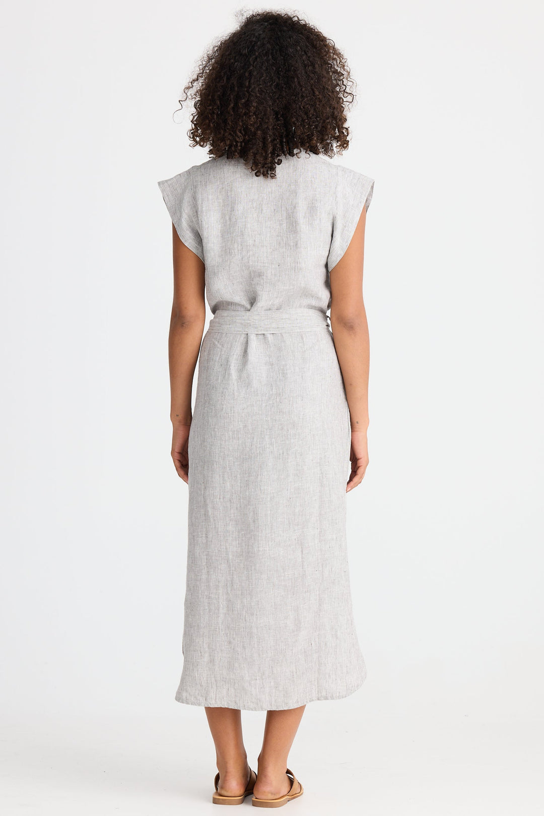 Woman wearing a light gray dress with a belt on a white background