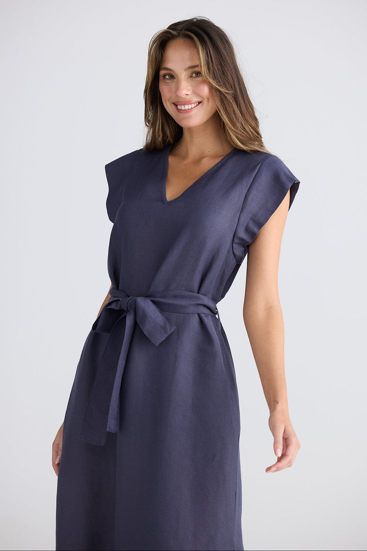Woman wearing a navy blue dress with a belt on a white background