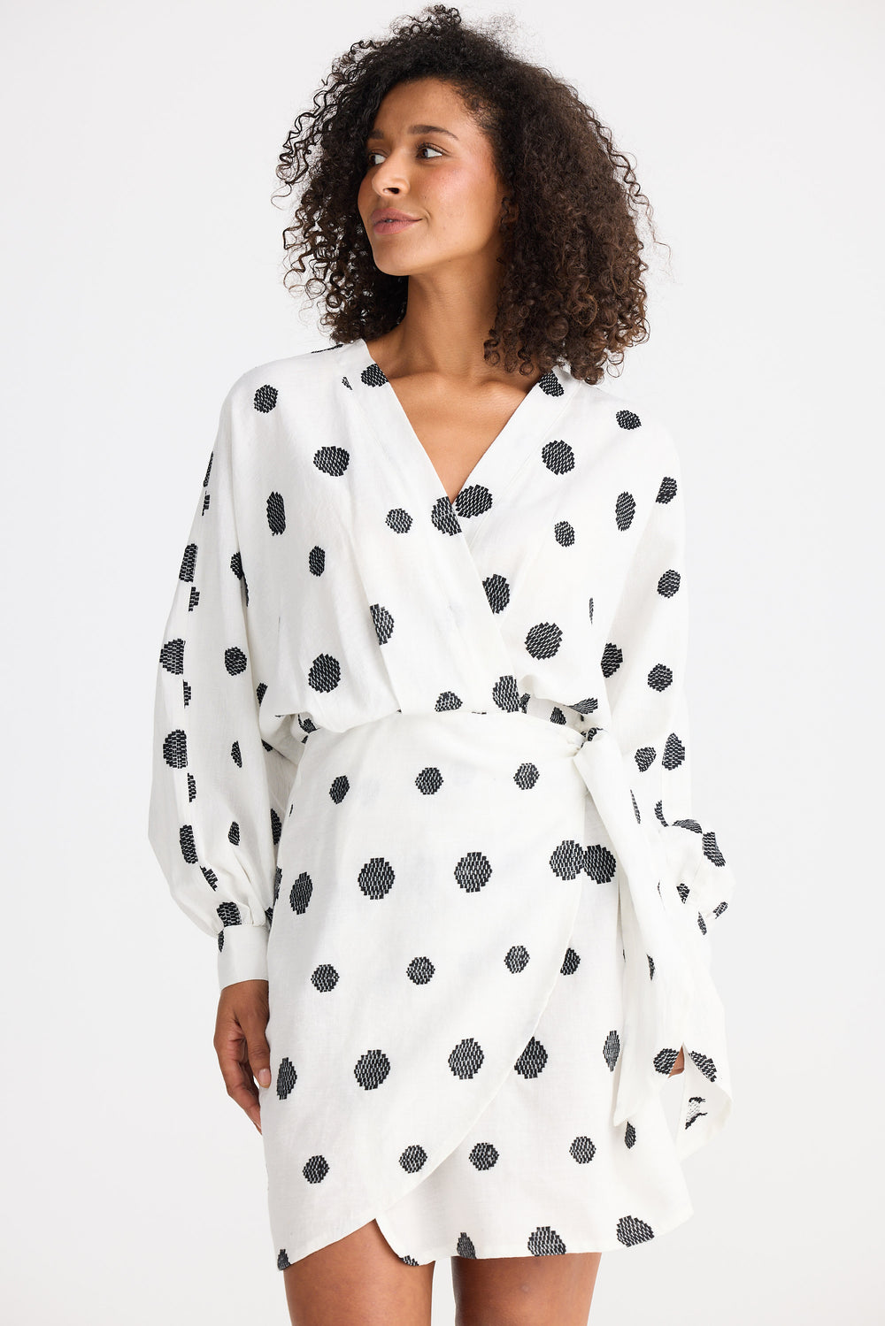 Woman wearing a white dress with black polka dots against a white background