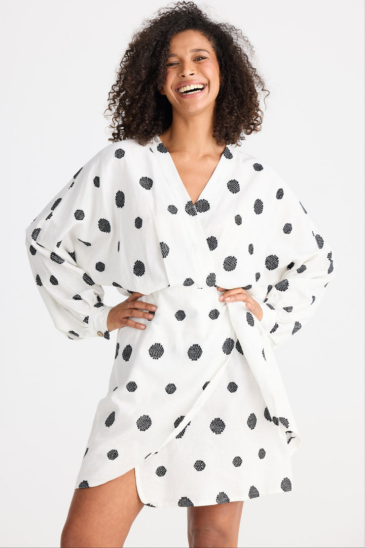 Woman wearing a white dress with black polka dots on a white background