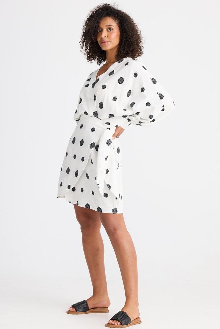 Woman wearing a white dress with black polka dots on a white background